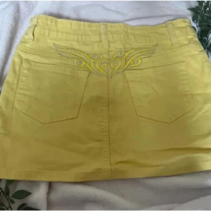 Gul jeanskjol från Juicy Couture - Gul mini jeanskjol med detaljer så som  broderi ovanför fickorna, knapp med guldfärgad ”kristall sten” och broderad J-logga framtill. Juicy couture liknande.💕Väldigt unik, jätte trendig färg och perfekt nu till sommar!😋 Storlek S-M