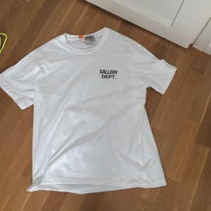 Vit t-shirt från Gallery Dept. - Vit t-shirt från Gallery Dept. med svart tryck fram och stort tryck på ryggen där det står 'GALLERY DEPT. HOLLYWOOD,CA. Allt orginal följer med påse allt hör av er vid funderingar 