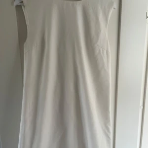 Vit ärmlös klänning med rosett - Superfin vit somrig eller studentklänning med ärmlös design och stor rosett i ryggen. Klänningen har en rak, enkel siluett. Endast använd en gång 💕