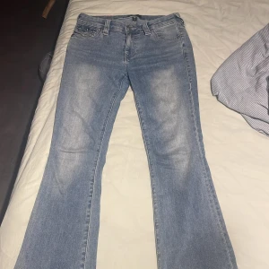 True Religion bootcut jeans ljusblå 💕 - Säljer ett par ljusblå bootcut jeans från True Religion som har varit  uppsydda men jag har sprätta upp dom så dom har lite avklippta i storlek W27 säljer dom för att dom är för stora för mig ❤️