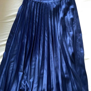 Mörkblå plisserad långkjol - Snygg mörkblå plisserad långkjol med glansig finish från Zalando. Bekväm och sparsamt använd! 