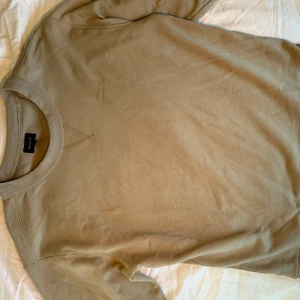Beige sweatshirt från GANT - Snygg beige sweatshirt från GANT med broderad logga på bröstet. Tröjan är bara använd någon enstaka gång och är i nyskick.  