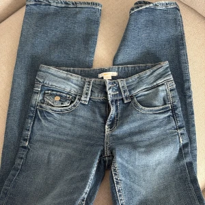 Blå jeans från Gina Tricot, stl 158 - Snygga blå jeans från Gina Tricot i klassisk femficksmodell. Jeansen har ljusa slitningar, kontrastsömmar och normal passform. Perfekta till vardags med en t-shirt eller hoodie. Materialet är tåligt denim i bomull.