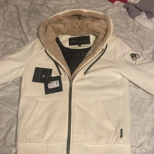 Vit teddyjacka från Moose Knuckles - Snygg/beige vit teddyjacka från Moose Knuckles med mjuk beige äkta päls som man kan ta av och på beroende på hur varmt de är. Köpt från room 1006 i Emporia malmö. Och andvänts på specifika dagar annars bara varit i garderoben. EXTREMT skön och fantastisk material och färgen kan inte kamera göra samman. Hör av er vid frågor 👍