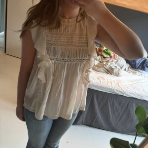 Beige blus med volanger och spets - Supersöt beige blus  med volangdetaljer längs sidorna. Köpt på Lindex och aldrig använd. Priset kan diskuteras🩷