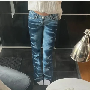 Blå bootcut jeans med coolt mönster -  Blå lågmidjade bootcut jeans med unikt blekt mönster längs benen. Storlek 27/30. Priset kan diskuteras🥰