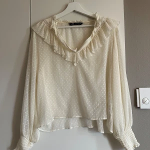 Vit blus med volanger från Zara - !Strl XL men sitter som en S/M! Superfin krämvit blus från Zara med fina detaljer som volangkrage, transparent strukturmönster och smock vid ärmsluten.