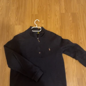 Mörkblå half zip tröja Polo Ralph Lauren - Mörkblå långärmad tröja från Polo Ralph Lauren med klassisk broderad logga på bröstet. Tröjan har en half zip-dragkedja och är tillverkad i mjuk bomull. Perfekt för lager-på-lager och chill stil. Storlek S men passar även M.