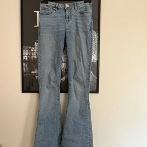 Ljusblå bootcut jeans med lågmidja  - Snygga ljusblå jeans med klassisk femficksdesign och bootcut-ben som ger en retrovibe. Jeansen är lågmidjade och är tillverkade i mjukt denimtyg. Perfekta för dig som vill ha en avslappnad men trendig look.