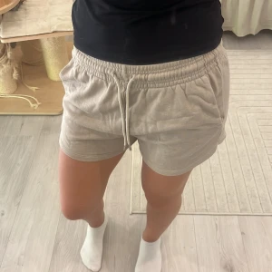 Beige mjuka shorts med snörning - Superbekväma beige shorts med elastisk midja och snörning framtill. De har en loose passform och är gjorda i ett mjukt bomullsmaterial, perfekta för varma sommardagar eller chill hemma. Enkla att matcha med allt och riktigt sköna att ha på sig.