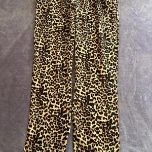 Leopardmönstrade byxor från Pieces M - Snygga byxor från Pieces i leopardmönster med elastisk midja. Byxorna är i mjuk och lätt LENZING ECOVERO viskos som känns skön mot huden. De har raka ben och en loose fit, perfekta för dig som vill sticka ut med din stil.