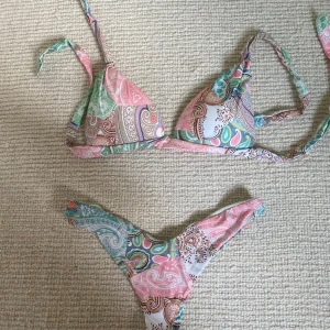 Pastellfärgad bikini med paisleymönster - Bikini från Calzedonia. Väldigt bra skick, använd fåtal gånger. Modellen säljs inte mer. Nypris 700kr. Sitter väldigt fint baktil i rumpan, (Brazilian/string). Det är även push på bhn så den sitter jätte fint. Storleken är borta men jag tror jag tog 70-75 C