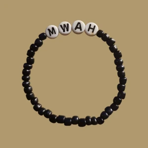 MWAH pärlarmband  - Ett stretchigt armband med svarta pärlor och vita bokstavspärlor som bildar ordet MWAH. Liten I storleken