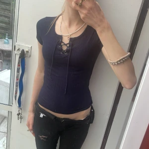 Snörning topp - Snygg mörkblå ribbad topp från Hollister med korta ärmar och snörning . Figurnära passform och mjukt stretchigt material som sitter perfekt. Passar xxs-s