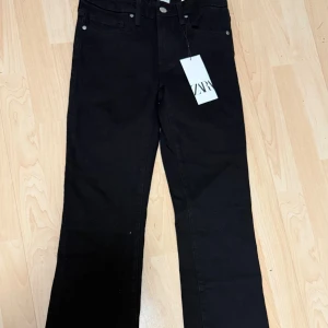 Svarta bootcut jeans från Zara - Snygga svarta bootcut jeans från Zara i modell The Contour Bootcut. Klassisk femficksdesign, hög midja och raka ben med lätt utsvängning. Jeansen är i mjuk bomullsblandning och har silverfärgade detaljer vid fickorna. Perfekta för en trendig och stilren look. Aldrig använda och prislapp på.
