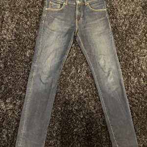 Mörkblå jeans från J.Lindeberg - Snygga mörkblå jeans från J.Lindeberg med klassiska fem fickor och kontrastsömmar. Jeansen har en smal passform och är tillverkade i jeansmaterial med en stilren look. Perfekta för dig som gillar en tajtare siluett.