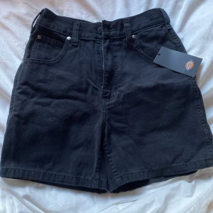 Svarta highwaist shorts från Dickies - Svarta shorts från Dickies med hög midja och klassisk femficksdesign. Tillverkade i kraftig bomull med raka ben och praktiska bakfickor. Perfekta för en chill och avslappnad look, med Dickies-logga på bakfickan. Storlek Xs men passar mig som har S!! (600kr och nypris är 799