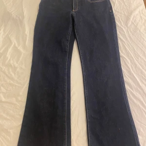 Mörkblå bootcut jeans från Abrand - Snygga mörkblå jeans från Abrand med klassisk bootcut-passform. Jeansen har låg midja, raka ben som blir vidare nertill och coola kontrastsömmar. 