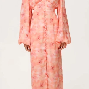 Lång Adoore blommig klänning med puffärm färgen Peach - Superfin långklänning ifrån Adoorei ljusrosa och persikotoner med blommigt mönster. Klänningen har v-ringning, knappar framtill och vida puffärmar. Snygg passform med markerad midja och flowy material som ger en romantisk vibe. Helt nya i förpackning. säljer flera storlekar 40,42,44,46,48,50 