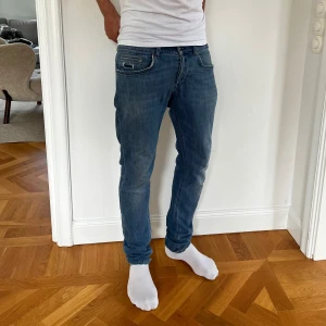 Dondup George jeans i blå färg - Säljer ett par riktigt snygga Dondup George jeans i ljusblå färg. De är perfekta nu till våren och sommaren. De har blivit använda men håller fortfarande ett bra skick. Som ni kan se på sista bilden är de lite slitna nedtill. Storlek 33. Skulle säga att de passar bra till någon med 29/32 ungefär. Köpta på NK i somras och säljs för 700:- Hör av er vid intresse!