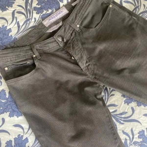 Jacob Cohën byxor  - Snygga grå byxor från Jacob Cohën i storlek 33. Byxorna har diskret rutigt mönster, klassisk femficksdesign och raka ben. Tillverkade i mjukt bomullsmaterial med en skön passform. Perfekta för dig som gillar stilrena och bekväma byxor. Kom med ev byten om så önskas.