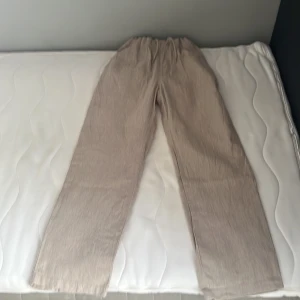 Beiga linnebyxor med snörning - Snygga beiga linnebyxor med elastisk midja och snörning. Byxorna har raka ben och sidfickor, perfekta för en chill och avslappnad stil. Lätta och luftiga i materialet, passar grymt till varma dagar. Använda 4-5 gånger 