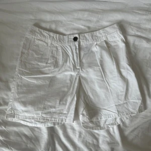 Vita bomullsshorts från H&M - Vita shorts från H&M i bomull med klassisk passform och normal midja. De har fickor på sidorna, knapp och dragkedja framtill samt uppvikta benslut för en clean look. Perfekta för varma dagar och enkel att matcha med allt