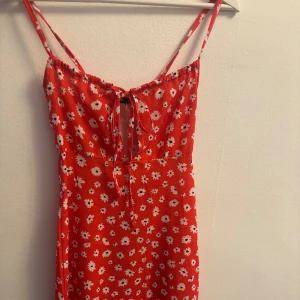 Röd blommig sommarklänning med knyt - Superfin röd kortklänning med vita blommor och smala axelband. 