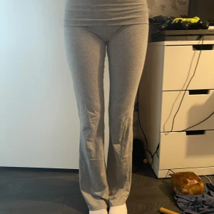 Grå bootcut yogapants - Säljer ett par ljusgrå mjukisbyxor med bootcut-snitt. Byxorna har hög midja och är gjorda i mjukt bomullsmaterial som är riktigt skönt mot huden. Perfekta för chill dagar eller när du vill vara bekväm men ändå se snygg ut.