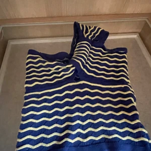 Randig blå och gul topp S - Superfin topp i blått och ljusgult (dåligt ljus) med vågiga ränder. Toppen har ett axelband  har en mjuk, stretchig passform, känns som stickad men luftigare, perfekt till sommaren. 