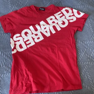  DSquared2 t-shirt  - Röd t-shirt från DSquared2 med stort vitt logotyp-tryck diagonalt över framsidan. Den är lite använd men är i bra skick. Hör av vid funderingar!