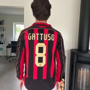 AC Milan Gattuso långärmad matchtröja - Säljer en klassisk AC Milan fotbollströja från Adidas med Gattuso och nummer 8 på ryggen. Tröjan är långärmad, har röda och svarta vertikala ränder, guldiga detaljer och klubbmärke på bröstet. Bwin-logga på framsidan och Champions League-märke på ärmen.