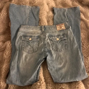 True Religion ljusblå bootcut jeans - Säljer ett par ljusblå bootcut jeans från True Religion som tyvärr är för stora för mig, bra skick ända nackdelen är att dom var för långa för mog så de är lite slitage på ena benet (sista bilden) öppen för prisförslag 