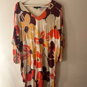 Ilse Jacobsen klänning  - Färgglad tunika/klänning med ett blommigt mönster i orange, gult och brunt. Den har en v-ringning. Passar perfekt för en avslappnad men stilfull look. Storlek S/M men stor i storleken tycker jag