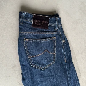 Jacob Cohen jeans - Snygga blå jeans från Jacob Cohen med klassisk femficksdesign och knappgylf. Perfekta för en stilren look. Priset är inte hugget i sten