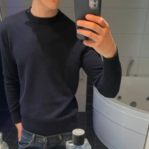 Mörkblå ulltröja från Massimo Dutti - Säljer en stilren mörkblå tröja från Massimo Dutti i mjuk ull. Tröjan har rund halsringning, ribbade muddar och lång ärm. Perfekt för dig som gillar en clean och klassisk look. Passar lika bra till jeans som till chinos.