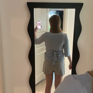 Ljusblå omlottblus från Vila - Supersöt ljusblå blus från Vila med trekvartsärm och knyt i midjan. Snygg omlottdetalj i ryggen och lätt, mjukt tyg som känns skönt mot huden. Perfekt till jeans eller kjol för en fräsch look.