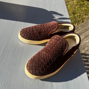 Bruna slip-on sneakers från Bottega Veneta - Otroligt snygga slip on skor från Bottega Veneta. Slutat säljas och därför svåra att få tag på. Perfekta skon till sommaren. Skick 9/10, bara använda enstaka gång. Priset är ej hugget i sten. Hör av dig vid minsta fundering!🙏⭐️