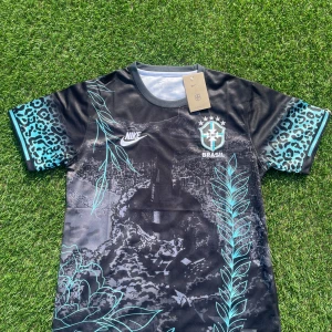 Nike Brasil svart fotbollströja L - Unik svart Brasil-fotbollströja från Nike med turkosa leopardmönstrade ärmar och detaljerade grafiska tryck framtill. Tröjan har korta ärmar, rund hals och är tillverkad i lätt Dri-FIT-material som andas. Perfekt för dig som vill sticka ut på planen.