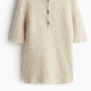 Beige stickad tröja med knappar - Supermjuk beige stickad tröja med korta ärmar och tre dekorativa knappar framtill. Tröjan har en fluffig känsla och är perfekt för lager-på-lager-stil. Enkel men ändå unik detalj med knapparna som ger en snygg touch. PRIS GÅR ATT DISKUTERAS!! Orginal pris 40€/400kr