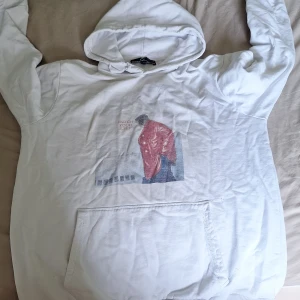 Vit hoodie med tryck från Chinwoo - Vit hoodie från Chinwoo med stor ficka framtill och huva. På bröstet finns ett tryck av en person i röd jacka och texten 'WATCH YOUR STEP'. Hoodien är i mjuk bomull och har en avslappnad passform, perfekt för chill dagar.