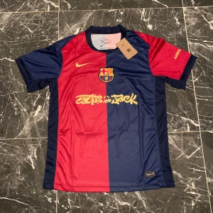 FC Barcelona Raphinha 11 Nike tröja M - Snygg FC Barcelona matchtröja från Nike i storlek M med Raphinha och nummer 11 på ryggen. Tröjan har klassisk halva-röd halva-blå design, klubbmärke på bröstet och gula detaljer. Tillverkad i lätt och ventilerande polyester, perfekt för fotboll eller att bära som supporter.