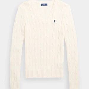 Vit kabelstickad tröja Polo Ralph Lauren - Kabelstickad vit tröja från Polo Ralph Lauren med klassisk v-ringning och broderad marinblå logga på bröstet. Långärmad modell i mjuk bomull, perfekt för lager-på-lager och stilren look. Älskar den!! Men säljer för att den är lite för liten! Den är mer vit/lite ljusrosa i verkligheten än på bilden. 💗