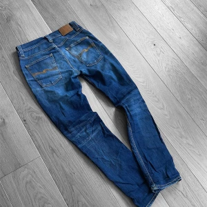 Nudie jeans grim Tim 31/32 - Säljer ett par feta nudie jeans i den populäraste modellen ”Grim Tim”! Jeansen har en snygg tvätt och en färg som passar året runt!!! Storleken är 31/32! Skriv vid funderingar!⚜️⚜️