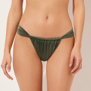 Olivgrön bikiniunderdel med snörning - Snygg olivgrön bikiniunderdel med scrunch-effekt och smala sidor med snörning. Modellen är tanga och har en glansig finish som ger en lyxig känsla. Perfekt för strandhäng och poolparty. Materialet känns mjukt och följsamt mot huden. De är från Calzedonia och ändrat testade tyvärr tog jag bort lappen därför kan jag ej lämna tillbaka.