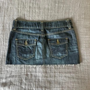 Lågmidjad jeanskjol från Esprit - Superfin jeanskjol från Esprit i mörkblå denim med lågmidja och fransig kant nertill. Kjolens bakfickor har snygga detaljer och färgen är jättesnygg. Den är lite för liten för mig som vanligtvis har M/38. 