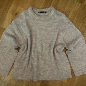 Beige stickad tröja från 157 - Mysig beige stickad tröja från 157 med rund halsringning och långa ärmar. Tröjan har en enkel och klassisk design med mjukt material som passar perfekt till vardagslooken.