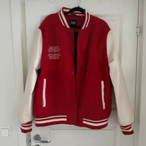 Röd och vit varsityjacka från Zara - Säljer en klassisk varsityjacka från Zara i rött och vitt. Jackan har vita ärmar, röda muddar med vita ränder och knappar framtill. Två fickor med vita detaljer och broderad text på bröstet. Tagit bort en klisterlapp samt sömnen har lossnat lite i armhålan (lagt in bilder) 
