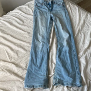 Ljusblå bootcut jeans - Säljer ett par ljusblå jeans med bootcut passform. Jeansen har klassisk femficksdesign, gylf med dragkedja och knapp samt normal midja. Perfekta för en avslappnad och trendig look.