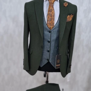Grön kostym med väst och orange accessoarer från Kenzal - Stilren grön kostym med matchande kavaj och väst i grått. Utrustad med orange slips, näsduk och blomdetalj. Klassisk passform och snygga knappar. Perfekt för bal eller fest. I olika färger. 2500 kr för en komplett som ingår Kostym/ byxor och väst. leverans tid är upp 1-17 arbetsdagar. Alla de är ny oanvända.